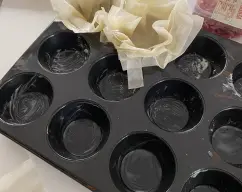 Step <p>Cada grupo de hojas, los he metido en unos moldes de cupcakes, así no se deforman. El molde lo he untado con mantequilla para que no se peguen.</p> illustration